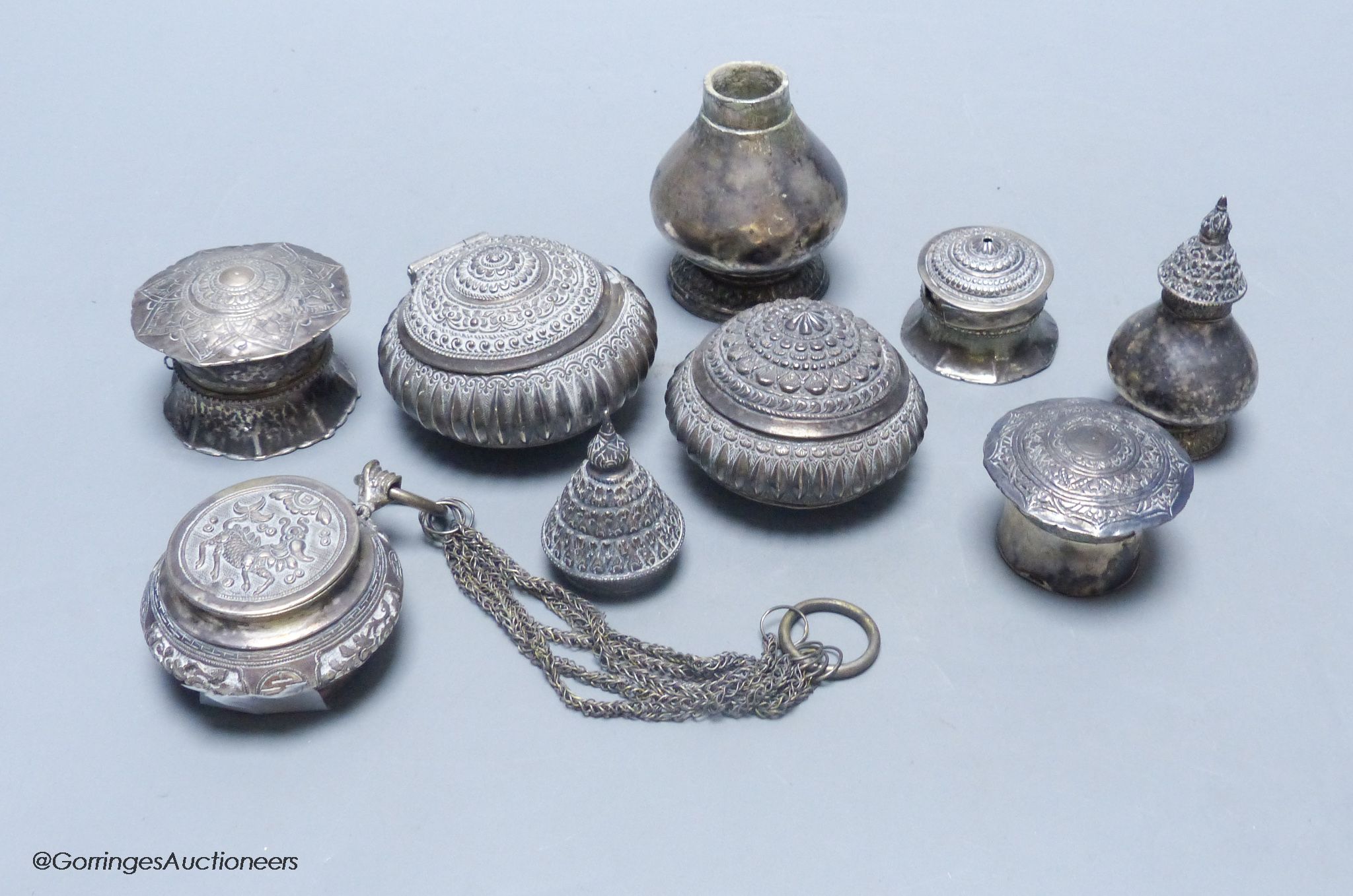 A Chinese white metal circular box and cover with multi-chain suspension, two Malay Straits white metal tobacco boxes ('Chelpa') and five similar lime boxes and covers